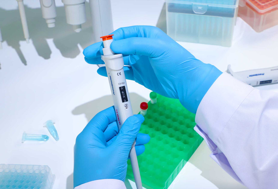 Close-up of hands handling a pipette in a laboratory.