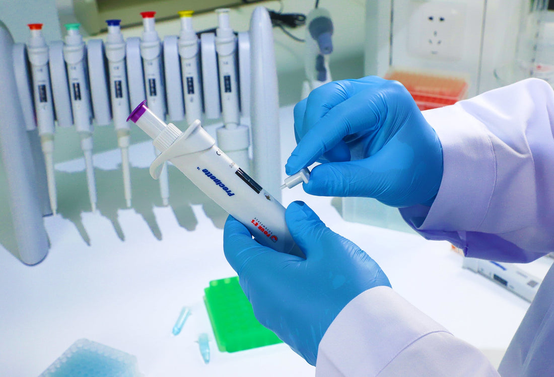 Close-up of hands calibrating a pipette near a pipette rack in a laboratory.